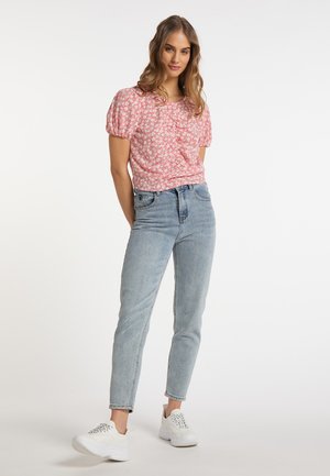 Kortærmet, lyserød blomsterbluse med puffærmer, parret med ljusblå højtaljede jeans og hvide sneakers. Enkelt, afslappet design.