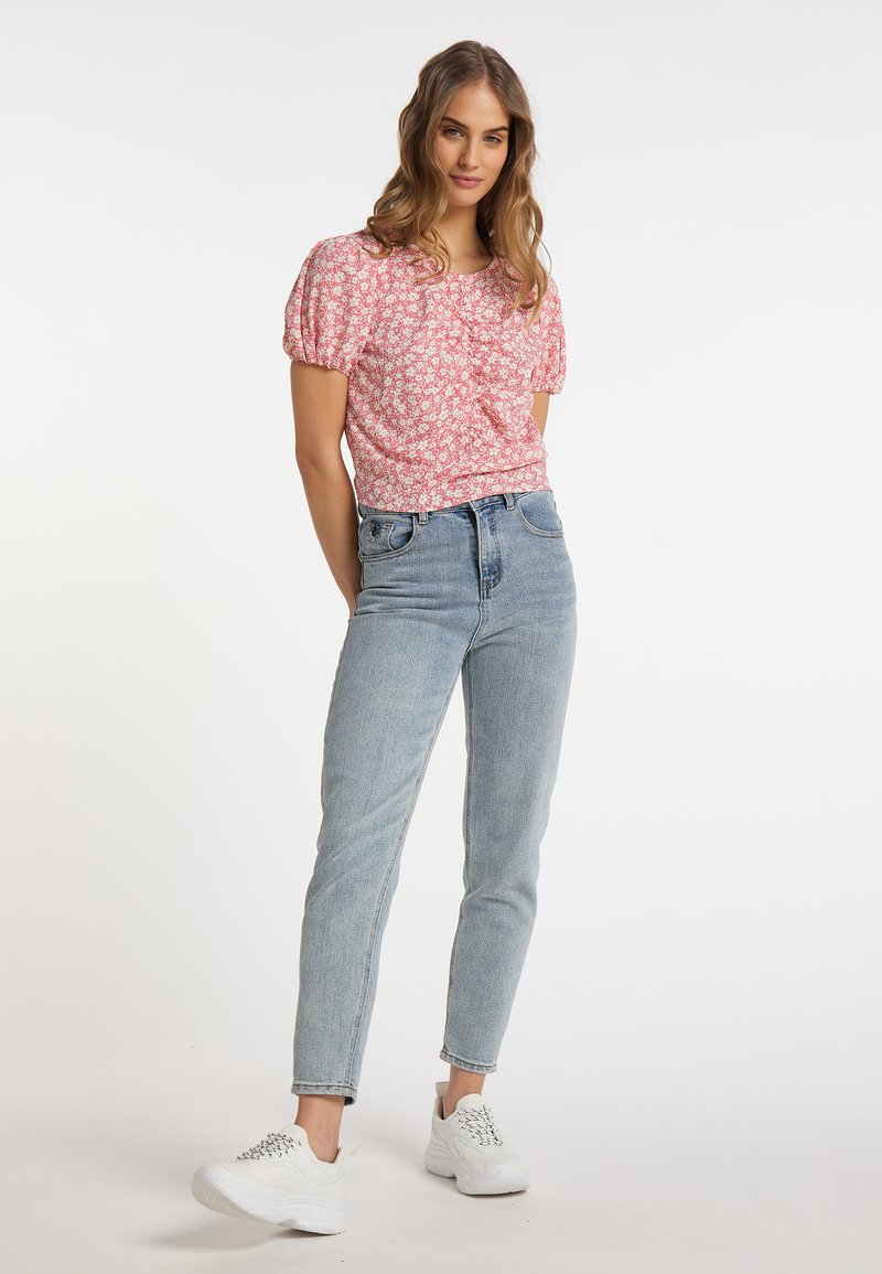 Kortærmet, lyserød blomsterbluse med puffærmer, parret med ljusblå højtaljede jeans og hvide sneakers. Enkelt, afslappet design.