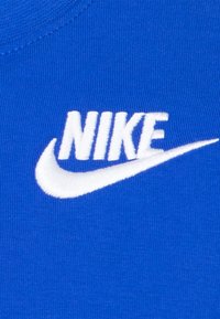 Nike mėlynas medvilninis marškinėlis su baltu išsiuvinėtu logotipu. Apvalus iškirpimas, lygaus paviršiaus ir trumpomis rankovėmis.