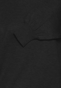 Čierny pulóver zo svetroviny s ribovanou textúrou, priliehavými rukávmi s nariasením a bezšvovým dizajnom. Klasický a univerzálny štýl.