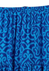 Tessuto a fantasia blu con disegni intricati in varie sfumature di blu. Il materiale è leggero con una parte superiore elastica arricciata.