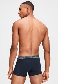 Dunkelblaue Boxershorts mit einem grauen elastischen Bund, der die "JACK & JONES"-Marke zeigt. Aus weichem Stoff mit enger Passform, entworfen für optimalen Tragekomfort.