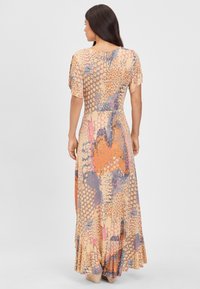 Maxi šaty, farebné s vzormi bodiek a šupín v oranžovej, fialovej a béžovej farbe. Ľahká tkanina s krátkymi volánovými rukávmi.