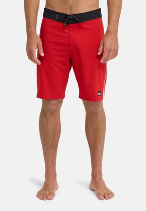 Rote Badeshorts aus leichtem Stoff, mit einem schwarzen Bund mit Kordelzug, Seitennähten und einem Logo-Patch am Bein.