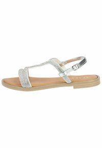 Vlakke zilveren sandalen met een getextureerde bovenkant die glanst. Verstelbare enkelband, tan voetbed en een lichtgewicht rubberen buitenzool.