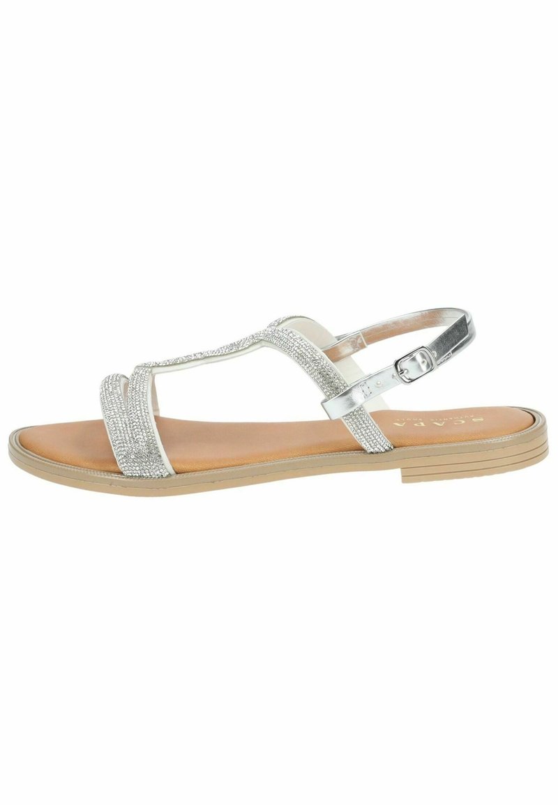 Vlakke zilveren sandalen met een getextureerde bovenkant die glanst. Verstelbare enkelband, tan voetbed en een lichtgewicht rubberen buitenzool.