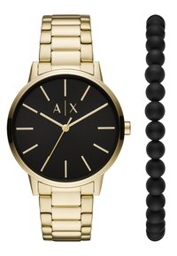 Reloj de metal dorado con una esfera redonda negra, marcadores dorados y una pulsera de eslabones. Acompañado de una pulsera de cuentas negras.