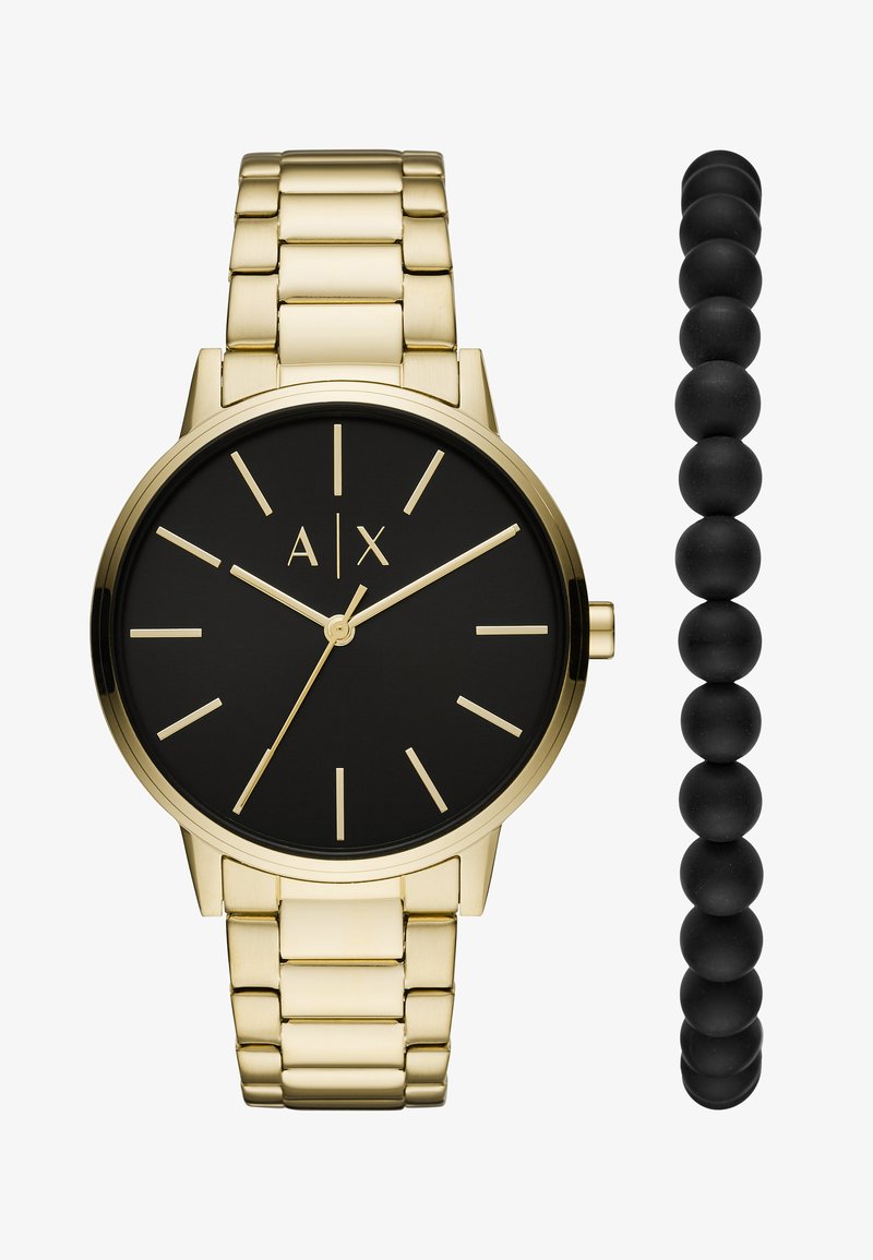 Orologio in metallo color oro con quadrante rotondo nero, marcatori dorati e bracciale a maglia. Accompagnato da un braccialetto con perle nere.