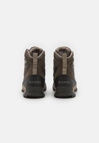 Brown hiking boots with soft textile upper, padded collar, and rubber sole. Features a logo on the heel and pull tabs for easy wear.