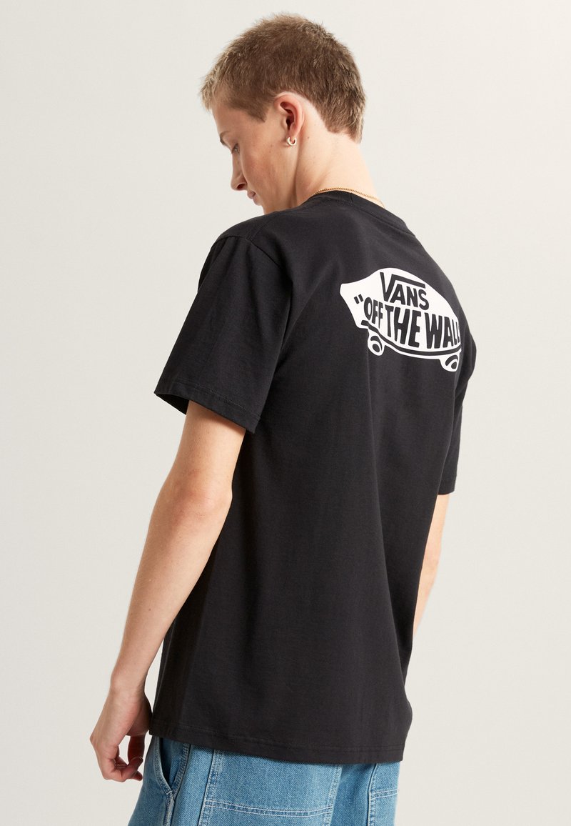 Czarna bawełniana koszulka z dużym białym napisem "VANS OFF THE WALL" na plecach, z okrągłym dekoltem i krótkimi rękawami.