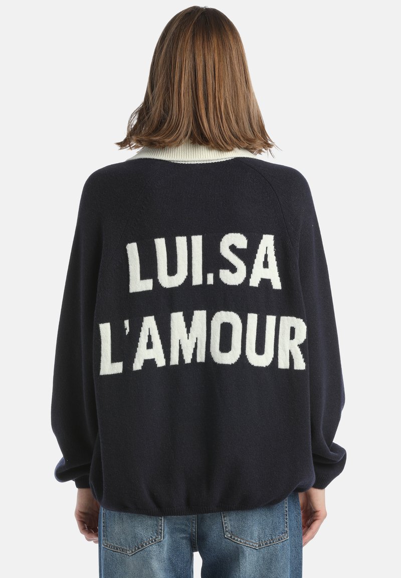 Námornícky pletený sveter s bielym rebrovaným golierom. Text "LUI.SA L'AMOUR" v masívnych bielych písmenách na chrbte. Nadmerné strih s dlhými rukávmi.
