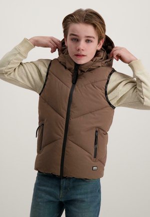 Brauner Puffer-Weste mit hohem Kragen und Kapuze, diagonaler Naht, zwei Reißverschlusstaschen und schwarzem Reißverschluss. Getragen über einem hellen Pullover.