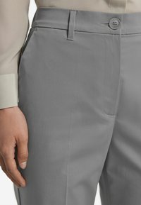 Jasnoszare, dopasowane spodnie o gładkiej fakturze, z zapięciem na guzik, kieszeniami bocznymi i slim fit.