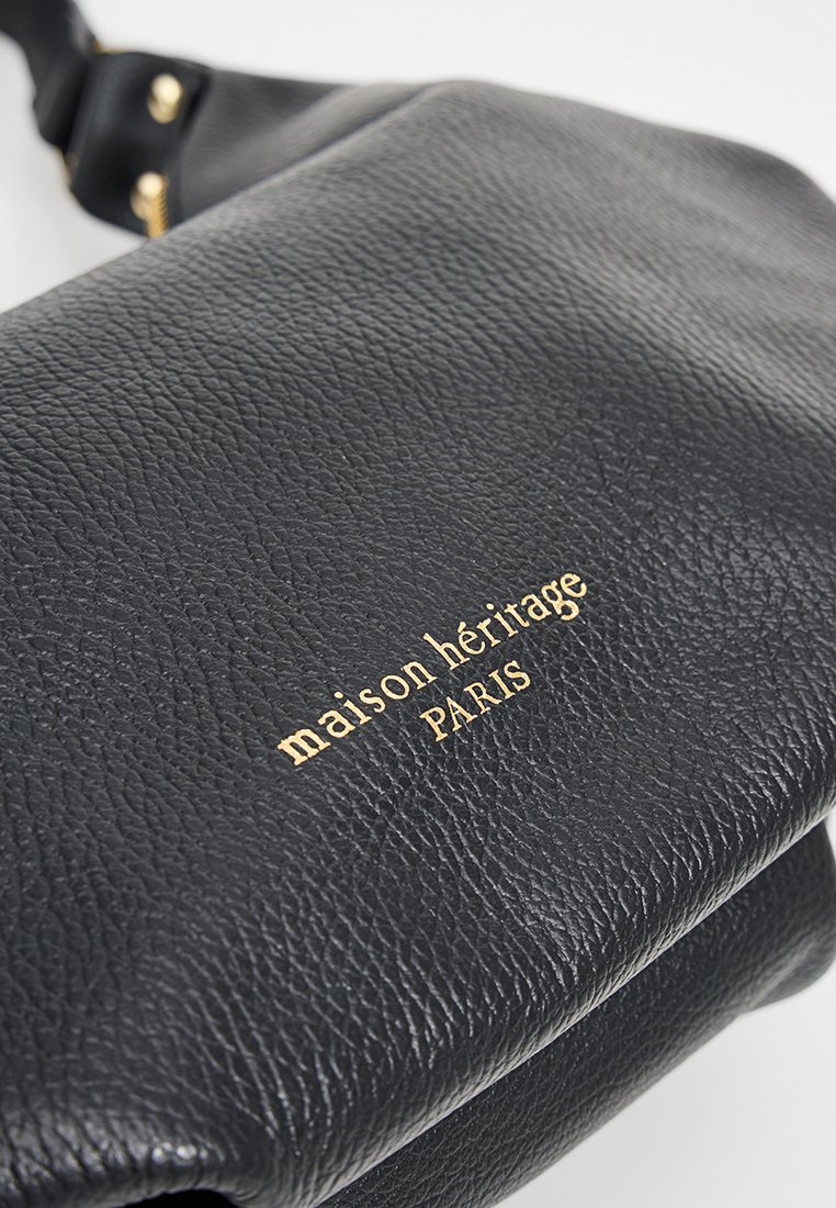 Sac en cuir noir à bandoulière, avec un matériau texturé, un logo doré en relief et un design plat avec une bandoulière réglable.