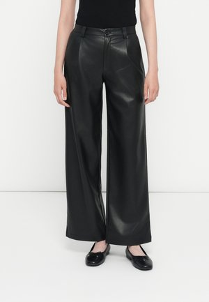 Zwarte faux leren wijde broek met een gladde textuur, hoge taille, voorkanten en een subtiele glans. Gecombineerd met zwarte platte schoenen.