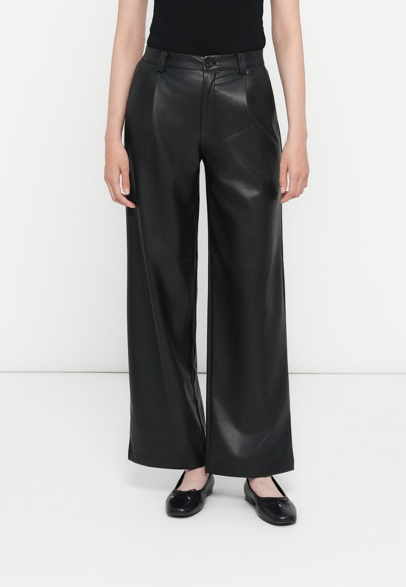 Zwarte faux leren wijde broek met een gladde textuur, hoge taille, voorkanten en een subtiele glans. Gecombineerd met zwarte platte schoenen.