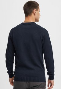 Navy blue knit sweater with a ribbed hem and cuffs. Features a round neckline and raglan sleeves. Smooth texture and medium weight.