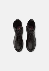 Stivaletti alla caviglia in pelle nera con texture liscia, dotati di chiusura frontale con lacci e cerniera laterale, punta arrotondata e linguetta per una facile calzata.