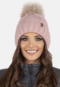 Berretto rosa lavorato a maglia con un pompon rotondo e soffice in pelliccia sintetica sulla parte superiore; presenta un design zigrinato a coste e una piccola patch in pelle.