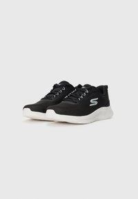 Pair of black athletic sneakers with white soles and a logo on the side, laced up, placed on a plain white background.