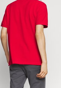 Rode katoenen T-shirt met korte mouwen en een ronde hals, van achteraf weergegeven. Heeft een effen textuur met een rechte zoom.