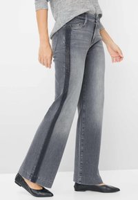 Bredde ben grå jeans med en mørk side-stribe, der har en tekstureret finish og en afslappet pasform. Parret med sorte flade sko og en lys grå top.