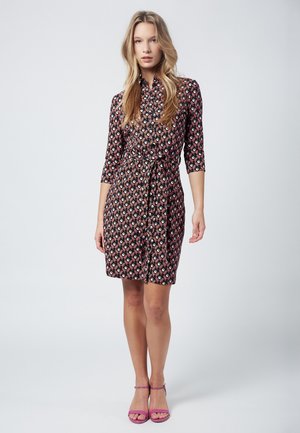 Black dress with geometric patterns in pink, orange, and blue. Features a buttoned collar and waist tie, with three-quarter sleeves.
