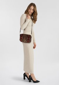Borsa a tracolla rettangolare con un tessuto stampato in marrone, rosso e oro, caratterizzata da una tracolla in pelle e dettagli in metallo dorato.