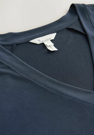 Donker marineblauw V-hals t-shirt van zacht materiaal, met een gladde textuur en een label met onderhoudsinformatie zichtbaar bij de halslijn.