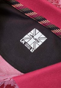 Bordeaux- en zwart stof met een gestructureerd patroon, voorzien van een etiket met de tekst "J&JOY UK" en een gestreepte kraag in rode en roze tinten.