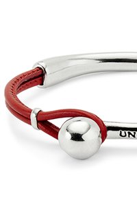 Primer plano de una pulsera de plata y roja con un cierre de plata liso, correas de cuero rojo y un adorno esférico de plata pulida.