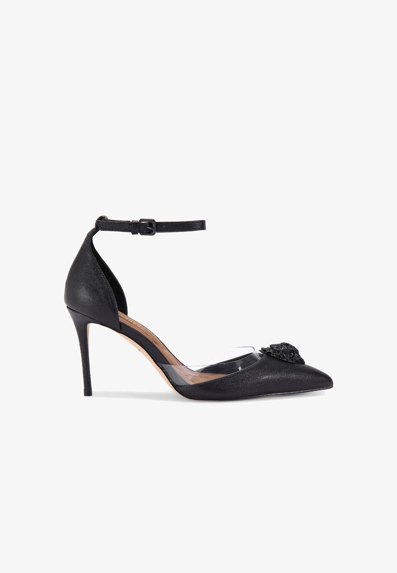 Chaussure noire à talons hauts avec un bout pointu, en tissu texturé, empeigne transparente et ornement noir décoratif à l'avant. Sangle de cheville réglable.