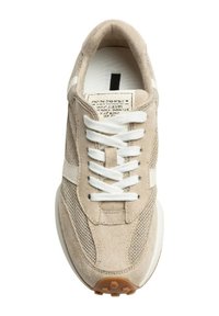 Zapatillas de ante y malla beige con cordones blancos, franja lateral y suela texturada. Presenta un diseño minimalista y una marca sencilla en la lengüeta.