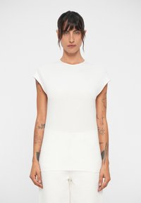 Haut blanc à manches courtes avec un col rond et une texture lisse, présentant un buste ajusté et un ourlet ample.