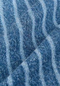 Tissu en denim avec un dégradé de tons bleus sombres à clairs, comportant un tissage texturé et de subtiles rayures horizontales.