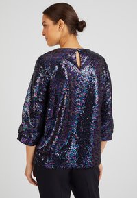 Black sequin top featuring a keyhole back detail, three-quarter sleeves, and iridescent shimmer throughout the fabric.