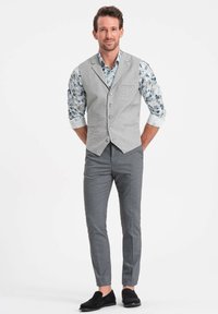 Gray vest with a textured pattern over a blue floral shirt, paired with slim-fit gray trousers and black loafers.