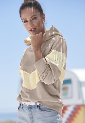 Beige and yellow pullover hoodie with chevron design, featuring lightweight fabric, drawstring hood, and ribbed cuffs. White belt with heart buckle.