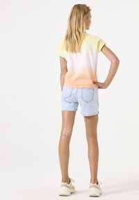Korte mouwen, gradient t-shirt in geel en oranje, gecombineerd met lichtblauwe denim shorts; relaxte pasvorm, eenvoudig ontwerp, zichtbare achternaden.