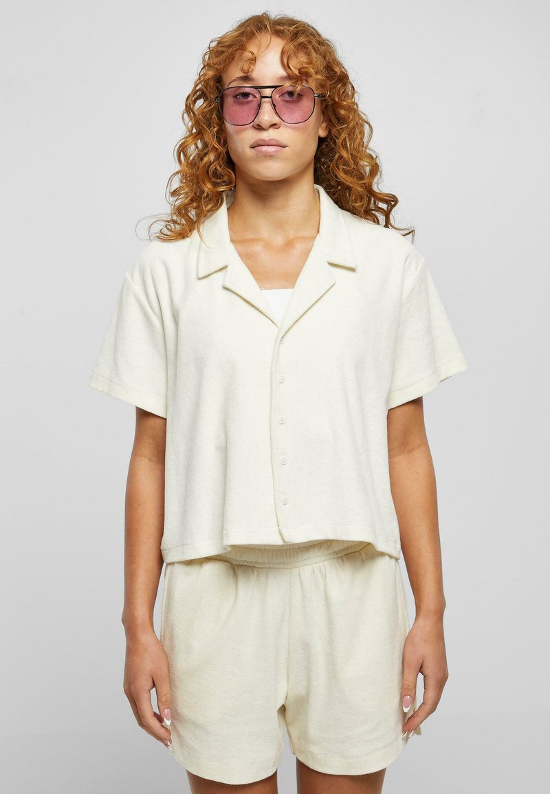 Off-white Kurzarm-Hemd mit Knöpfen und lässiger Passform, kombiniert mit passenden Shorts. Der Stoff wirkt weich und hat eine subtile Textur.