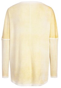 Vaaleankeltainen ylisuuri neule, ribattu pinta, leveä kaula-aukko ja pitkät hihat, joissa on hienovaraisia valkoisia yksityiskohtia ja ompelutaitoksia.