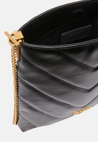 Borsa a mano in pelle nera con motivo trapuntato, accessori in oro e chiusura con zip. Presenta un'etichetta interna con il marchio. Finitura testurizzata.