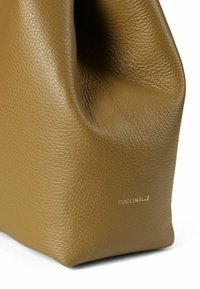 Borsa a mano in pelle marrone con una finitura morbida e strutturata. Presenta una forma unica e un marchio discreto. Senza parti metalliche visibili.