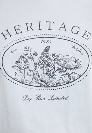 Heledhall hallatav puuvillane särk, millel on must lilleline graafika, ümbritsetud ovaalse piirjoonega, millel on tekst "HERITAGE", "1979" ja "Big Star Limited".