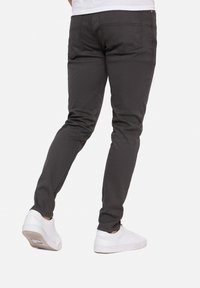 Tummanharmaat, kapenevat farkut, jotka on valmistettu puuvillasekoitekankaasta. Niissä on sileä pinta ja näkyvät ompelusaumat. Yhdistetty valkoisiin tennareihin.