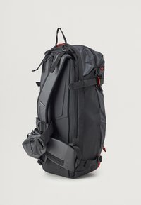 Zaino nero con un design strutturato, materiale resistente, spallacci regolabili, dettagli in metallo arancione e maniglia superiore per il trasporto.