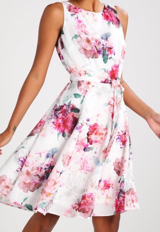 Sleeveless white dress with pink, red, and purple floral print, fitted waist, and flared skirt worn by a person with arms extended.