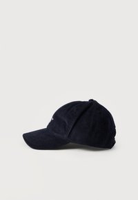 Καπελάκι μπέιζμπολ σε σκούρο ναυτικό μπλε βελούδο κοτλέ με κυρτή γείσο, εμφανιζόμενο σε απλό ανοιχτό φόντο, πλάγια όψη.