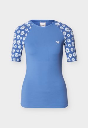 Blå kortermet rashguard med hvite prestekrage-mønstre på ermene og liten hvit logo på venstre bryst.