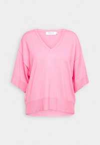 Pull rose à manches courtes et col en V, coupe ample, avec poignets et ourlet côtelés, présenté sur un fond clair uni.